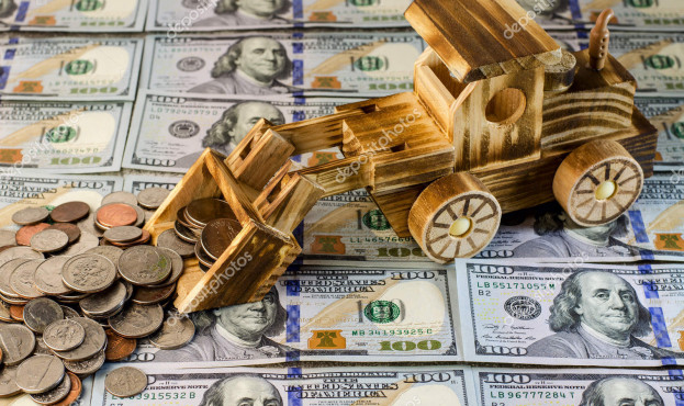 A toy tractor rakes a bunch of US cents against a background of