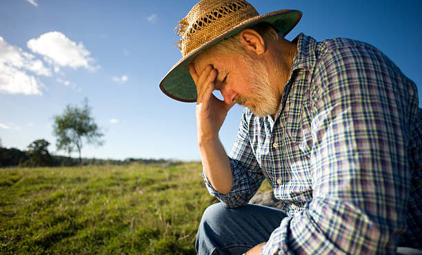 Photograph of a farmer thinking with his head in his hand.