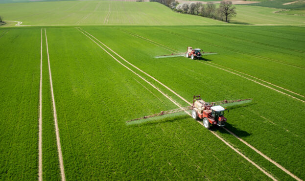 Aerial,View,Of,The,Tractor,Spraying,The,Chemicals,On,The